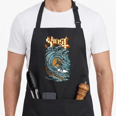 Tablier de cuisine noir avec illustration d'un fantôme surfeur dans une vague aux têtes spectrales et le mot Ghost en lettres gothiques.