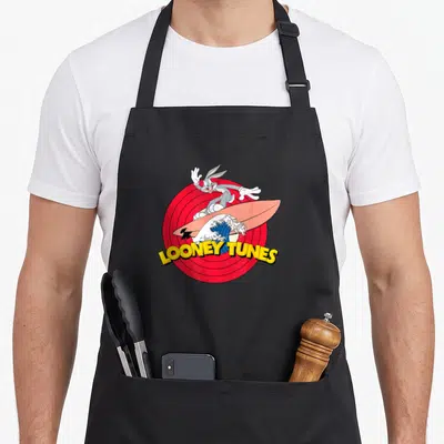 Tablier de cuisine noir avec Bugs Bunny surfant sur une planche rose devant un logo Looney Tunes rouge et jaune.