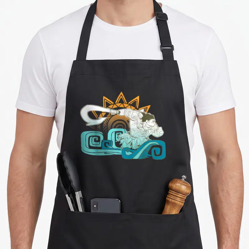 Tablier de cuisine noir avec illustration de Maui tenant son crochet au-dessus de vagues bleues et d'un soleil orange.