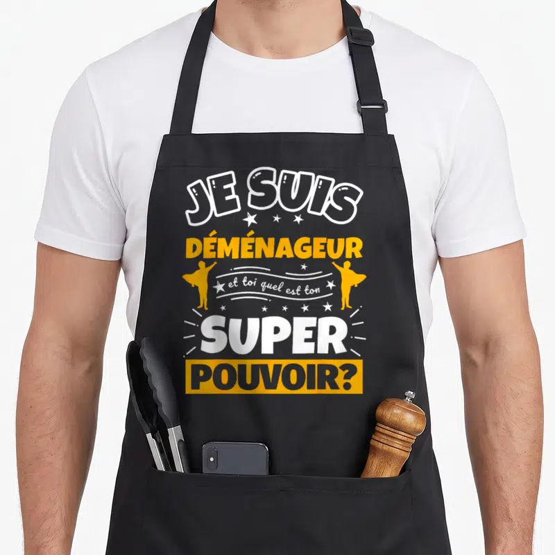Tablier de cuisine noir avec inscription Je suis déménageur et toi quel est ton super pouvoir en orange et blanc.