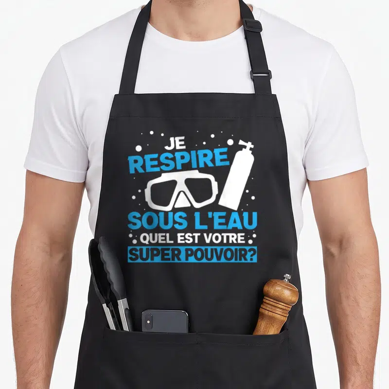 Tablier de cuisine noir avec masque de plongée, bouteille d'air et texte Je respire sous l'eau super pouvoir en bleu et blanc.
