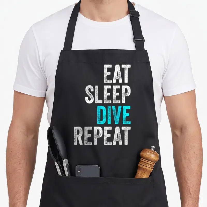 Tablier de cuisine noir avec le texte Eat Sleep Dive Repeat en blanc et cyan