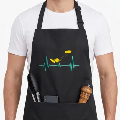 Tablier de cuisine noir avec un kiteboard jaune sur une ligne de rythme cardiaque turquoise.