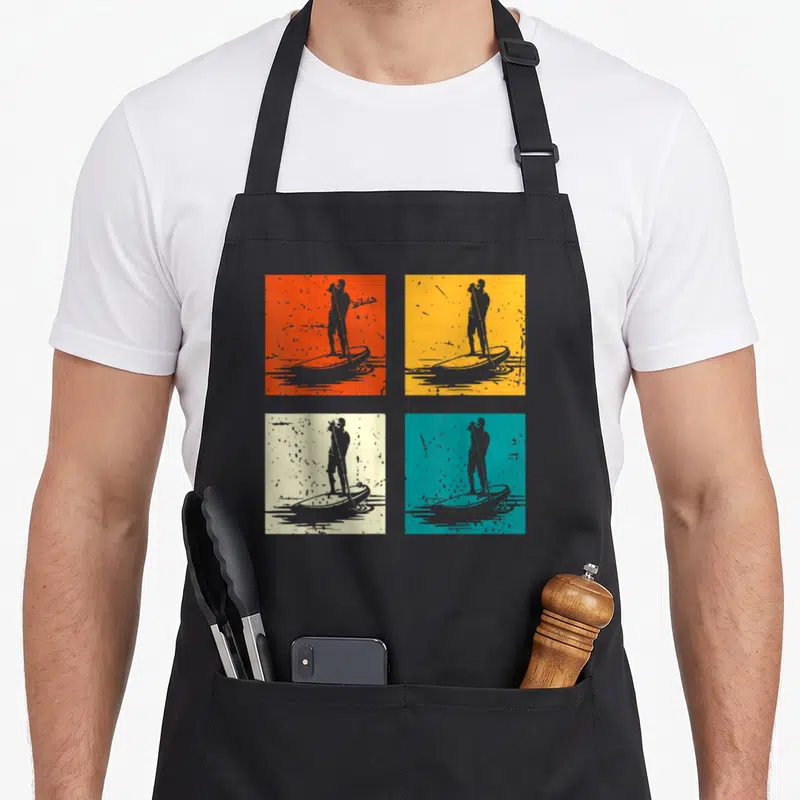 Tablier de cuisine noir avec quatre illustrations de planche à pagaie sur fonds colorés style pop art.