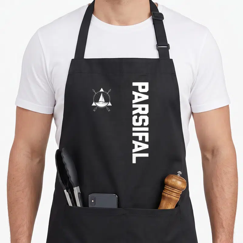 Tablier de cuisine noir avec logo voilier boussole et texte vertical Parsifal Chemise de voile en blanc.