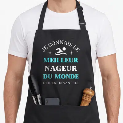 Tablier de cuisine noir avec une illustration de nageur et un texte humoristique en blanc et turquoise.