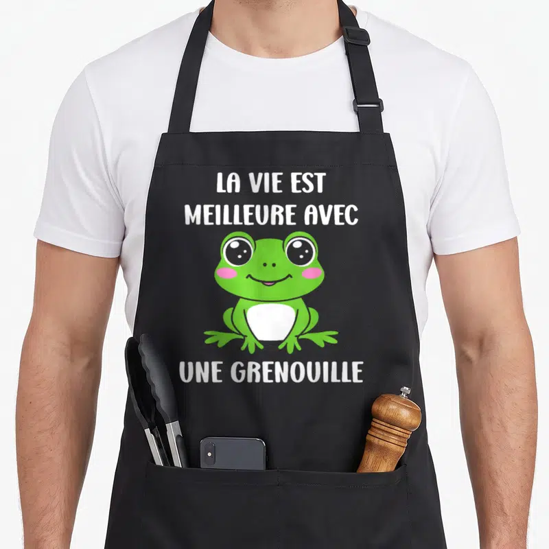 Tablier de cuisine noir avec une petite grenouille verte souriante et le texte La vie est meilleure avec une grenouille en blanc.