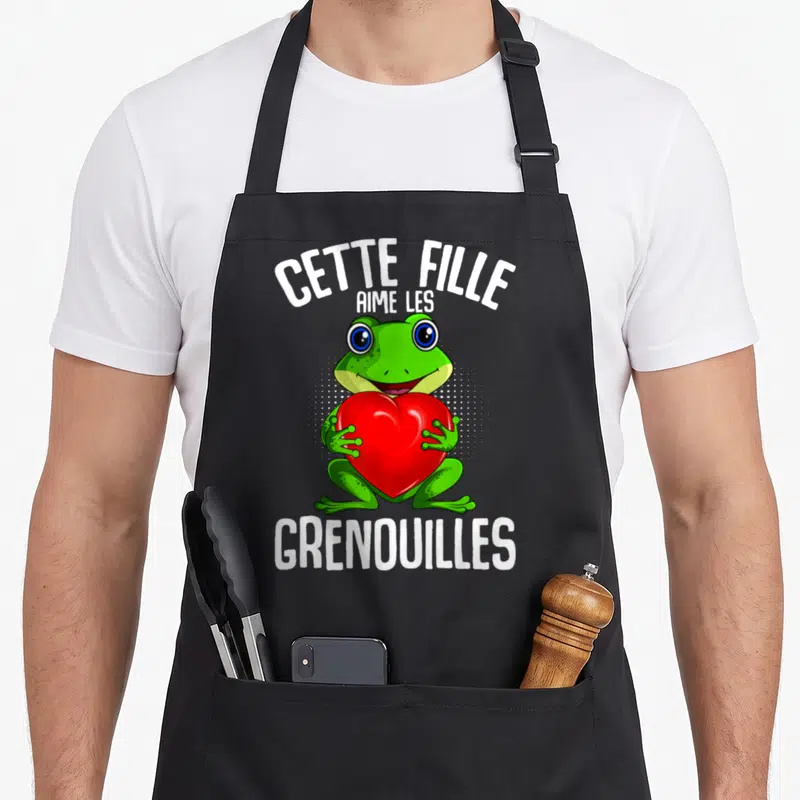 Tablier de cuisine noir avec une grenouille verte tenant un cœur rouge et du texte blanc.