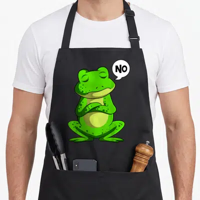 Tablier de cuisine noir avec illustration d'une grenouille verte têtue et la bulle NO.