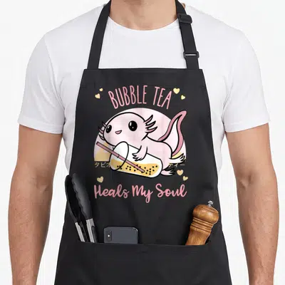 Tablier de cuisine noir avec un axolotl rosetenant un bubble tea et le texte Bubble Tea Heals My Soul en lettres roses.