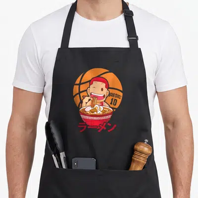 Tablier de cuisine noir avec personnage d'anime mangeant du ramen devant un ballon de basket orange.