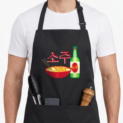 Tablier de cuisine noir avec illustration d'un bol de ramen rouge, d'une bouteille verte de soju et de caractères coréens rouges stylisés.