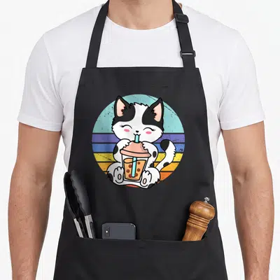 Tablier de cuisine noir avec un chat blanc et noirtenant un verre de thé boba à la paille bleue sur fond circulaire pastel.