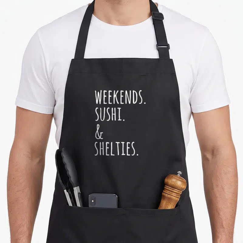 Tablier de cuisine noir avec inscription blanche Weekends Sushi et Shelties en typographie manuscrite.