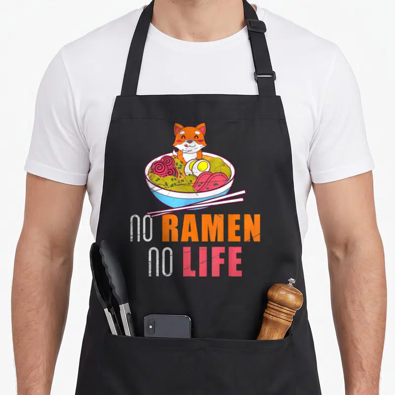 Tablier de cuisine noir avec illustration d'un Shiba Inu dans un bol de ramen et texte No Ramen No Life.