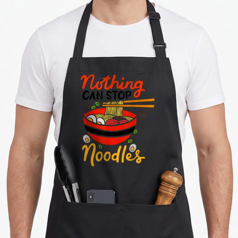 Tablier de cuisine noir avec illustration colorée d'un bol de ramen et texteNothing Can Stop Noodles