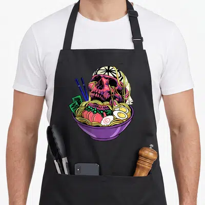 Tablier de cuisine noir avec illustration d'un crâne de ramen dans un bol violet aux couleurs vives.