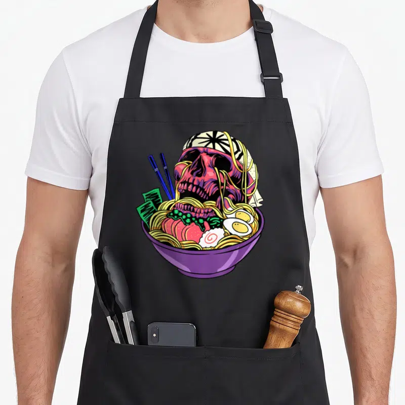 Tablier de cuisine noir avec illustration d'un crâne de ramen dans un bol violet aux couleurs vives.