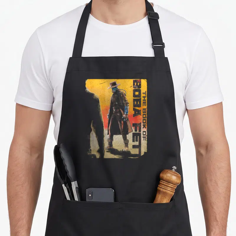 Tablier de cuisine noir avec illustration vintage de Cad Bane et texte The Book of Boba Fett sur fond orange dégradé.