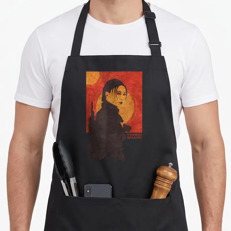 Tablier de cuisine noir avec illustration Fennec Shand et texte Red Tatooine sur fond rouge texturé.
