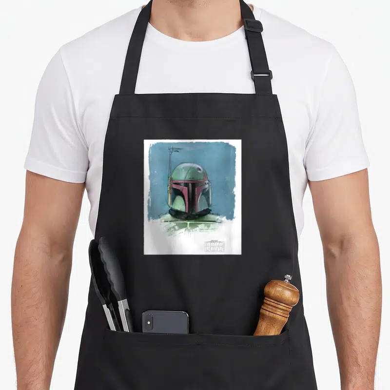 Tablier de cuisine noir avec illustration colorée du casque de Boba Fett sur fond bleu texturé.