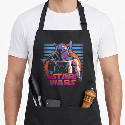 Tablier de cuisine noir avec illustration de Boba Fett en néon rose et bleu sur fond orange, texte Star Wars en bas.