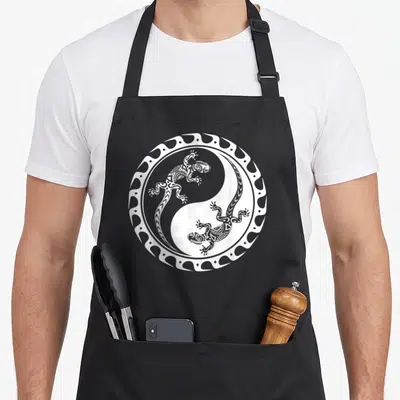Tablier de cuisine noir avec illustration blanche d'une salamandre maori dans un cercle yin yang tribal polynésien.