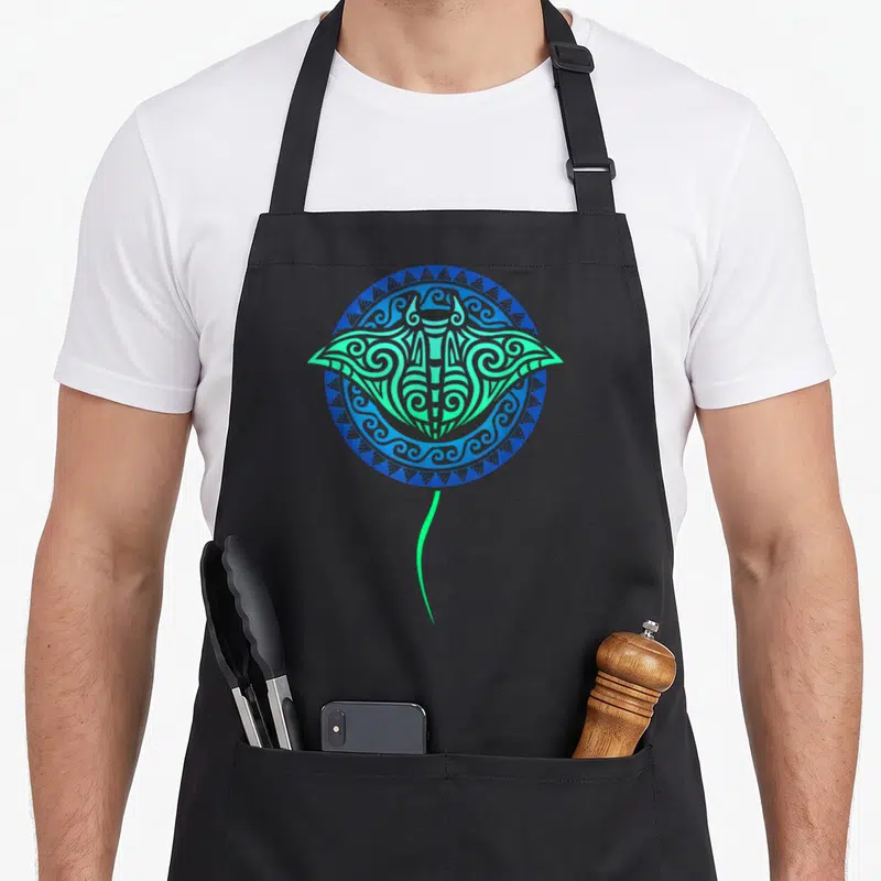 Tablier de cuisine noir avec une raie manta verte et bleue au motif tribal polynésien circulaire.