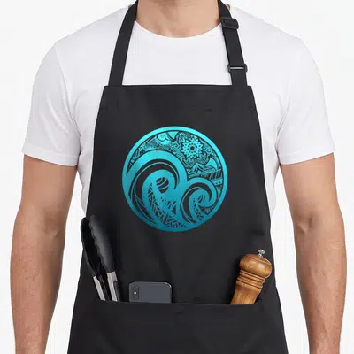Tablier de cuisine noir avec motif circulaire turquoise représentant des vagues et des motifs tribaux polynésiens.