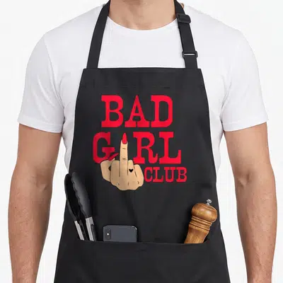 Tablier de cuisine noir avec illustration main doigt d'honneur et texte Bad Girl Club en rouge vif.
