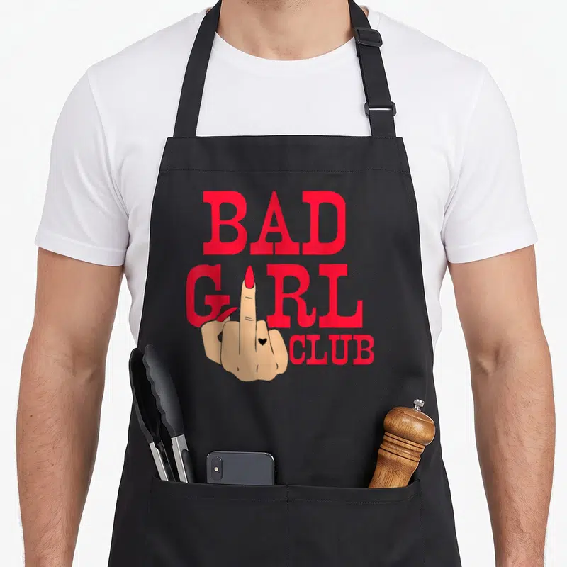 Tablier de cuisine noir avec illustration main doigt d'honneur et texte Bad Girl Club en rouge vif.