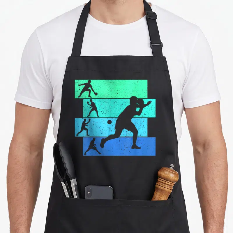 Tablier de cuisine noir avec silhouettes de joueurs de tennis de table sur bandes colorées dégradées.