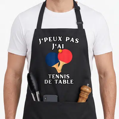 Tablier de cuisine noir avec inscription Je peux pas j'ai tennis de table et deux raquettes colorées.