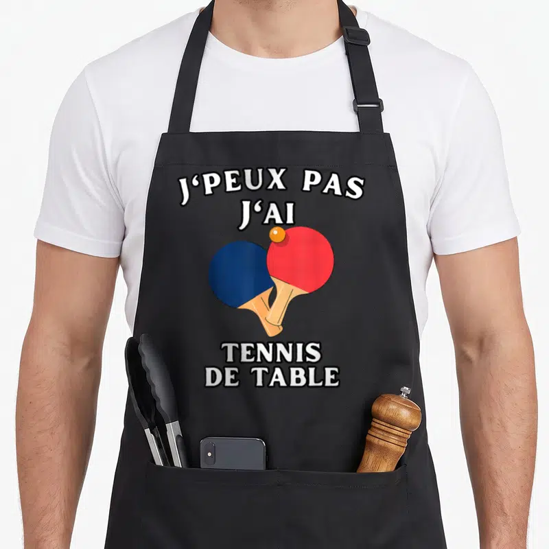 Tablier de cuisine noir avec inscription Je peux pas j'ai tennis de table et deux raquettes colorées.