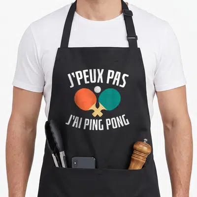 Tablier de cuisine noir avec inscription Je peux pas j'ai ping pong et deux raies de tennis de table croisées orange et verte.