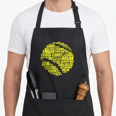 Tablier de cuisine noir avec un motif typographique jaune représentant une balle de tennis composée de termes de jeu.