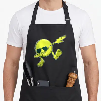 Tablier de cuisine noir avec une balle de tennis jaune anthropomorphisée portant des lunettes noires et effectuant un dab.