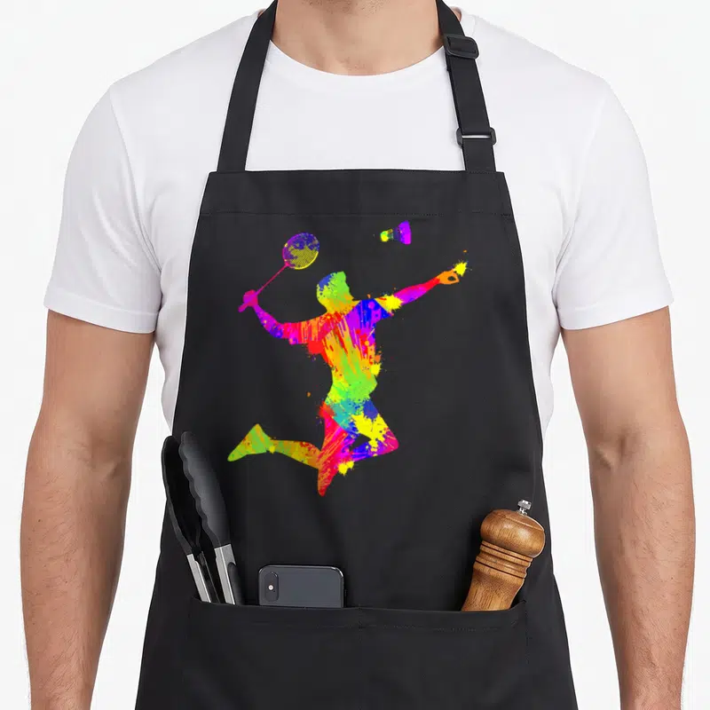 Tablier de cuisine noir avec silhouette multicolore d'un joueur de badminton en pleine action avec raquette et volants.