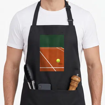 Tablier de cuisine noir avec illustration de court de tennis orange, lignes blanches et balle de tennis jaune fluorescente au centre.
