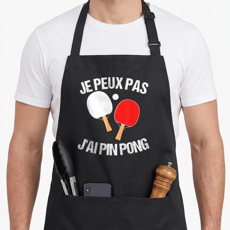 Tablier de cuisine noir avec deux raquettes de ping-pong et le texte Je peux pas j'ai ping pong.