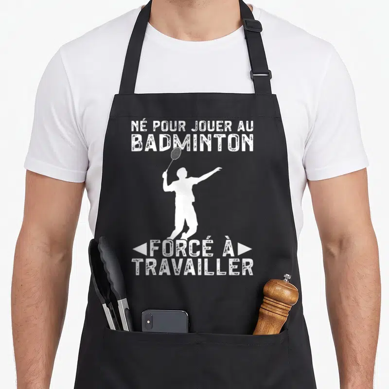 Tablier de cuisine noir avec une silhouette blanche de joueur de badminton et du texte humoristique en blanc.