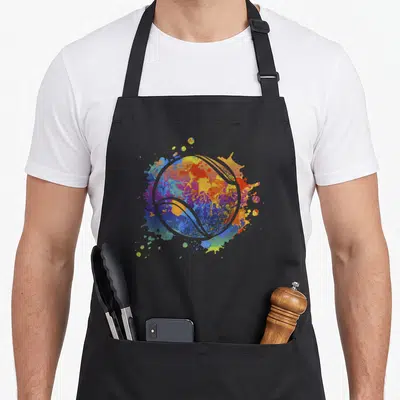 Tablier de cuisine noir avec une balle de tennis stylisée aux éclats de peinture colorée.