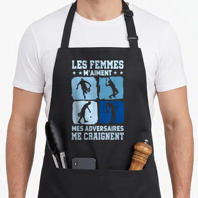 Tablier de cuisine noir avec quatre cases bleues montrant des silhouettes de joueurs de padel et du texte humoristique en blanc.