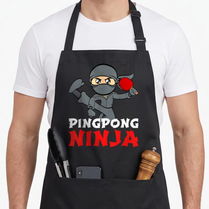Tablier de cuisine noir avec un ninja gris tenant une raquette de ping-pong rouge et le texte Pingpong Ninja.