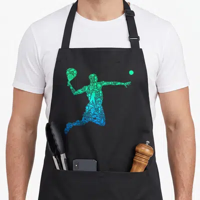 Tablier de cuisine noir avec silhouette de joueur de padel composée d'icônes sportives vertes et bleues.