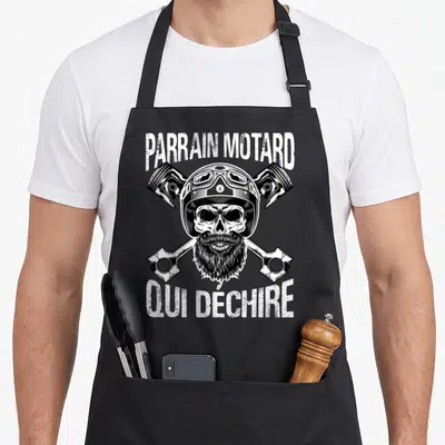 Tablier de cuisine noir avec une tête de mort tatouée à casque et pistons croisés.