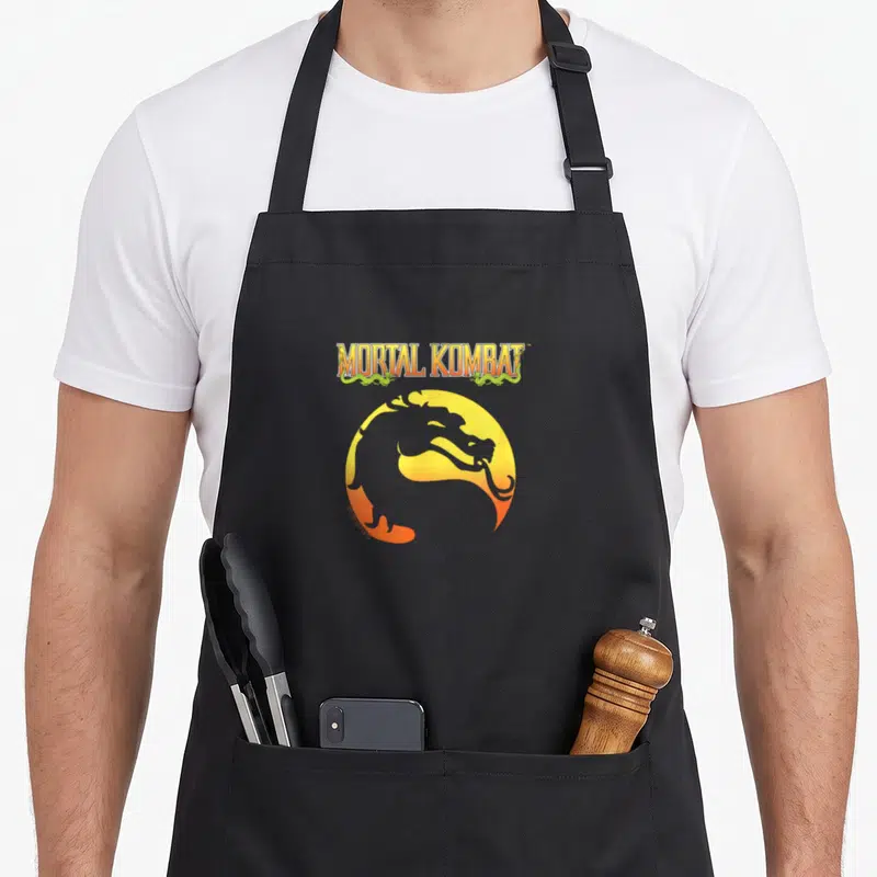 Tablier de cuisine noir avec le logo Mortal Kombat Klassic et un dragon stylisé orange sur fond circulaire jaune.