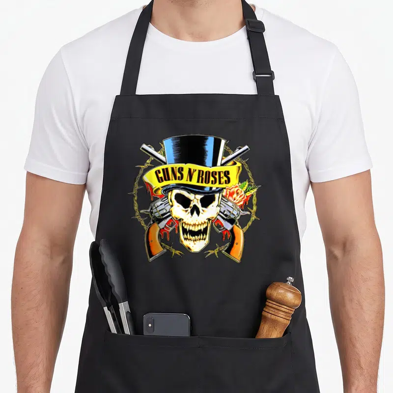 Tablier de cuisine noir avec tête de mort coiffée d'un chapeau haut-de-forme et des revolvers croisés.
