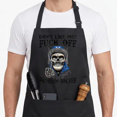 Tablier de cuisine noir avec crâne moustachu, casquette bleue et texte provocateur en anglais.
