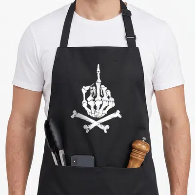 Tablier de cuisine noir avec une main squelettique faisant un doigt d'honneur sur des os croisés en blanc.